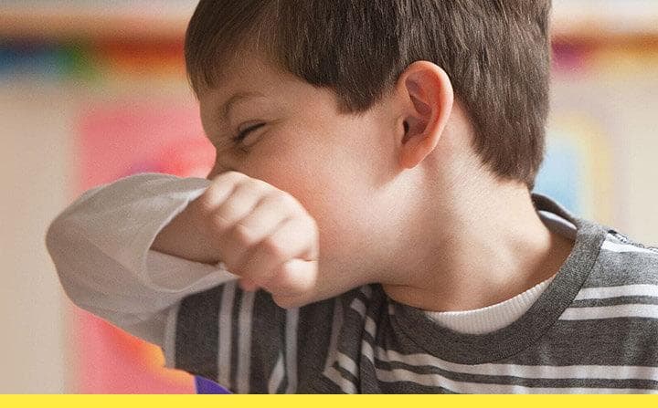 Young boy wiping his nose on his shirt sleeve