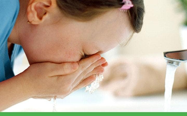young brown-haired child child splashing her face with water