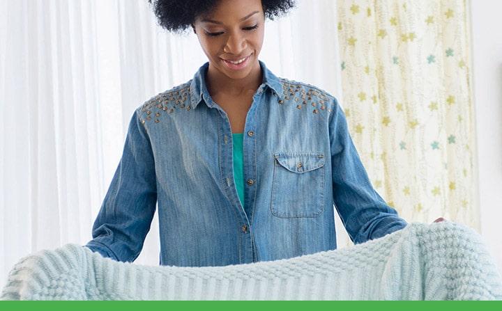 smiling woman preparing to fold away a blanket in the living room